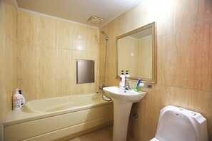 Une salle de bain équipée d’une baignoire, d’un lavabo, d’un miroir et d’articles de toilette.