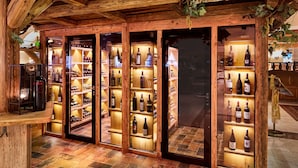 A wine cellar with wooden shelves and glass doors, displaying various bottles of wine. - Hotel Seehof (Koessen)