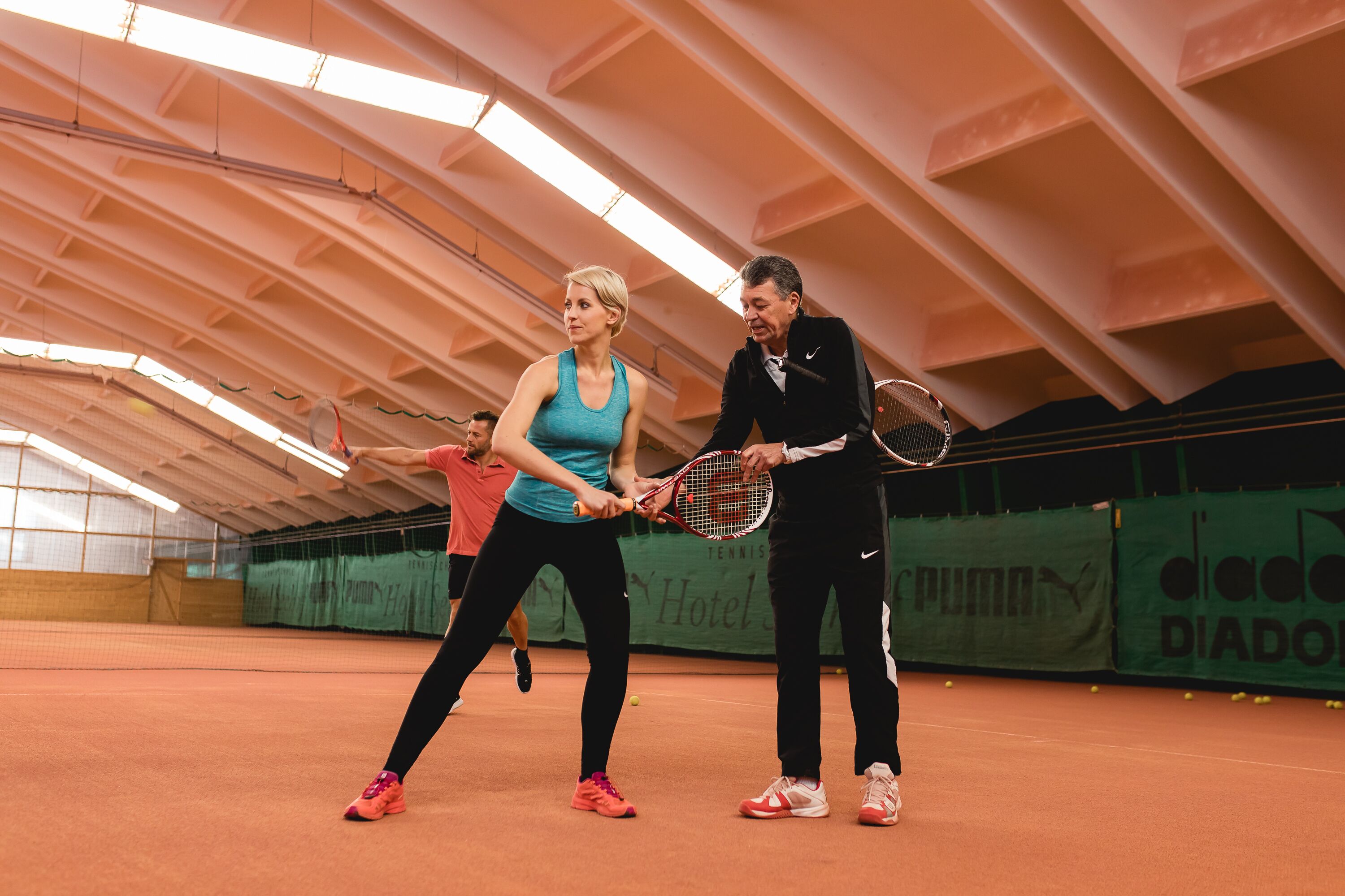 Una cancha de tenis interior con techo alto y un cartel verde que anuncia un hotel.