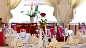 Una mesa de comedor dispuesta con servilletas blancas, cubiertos y cristalería transparente.