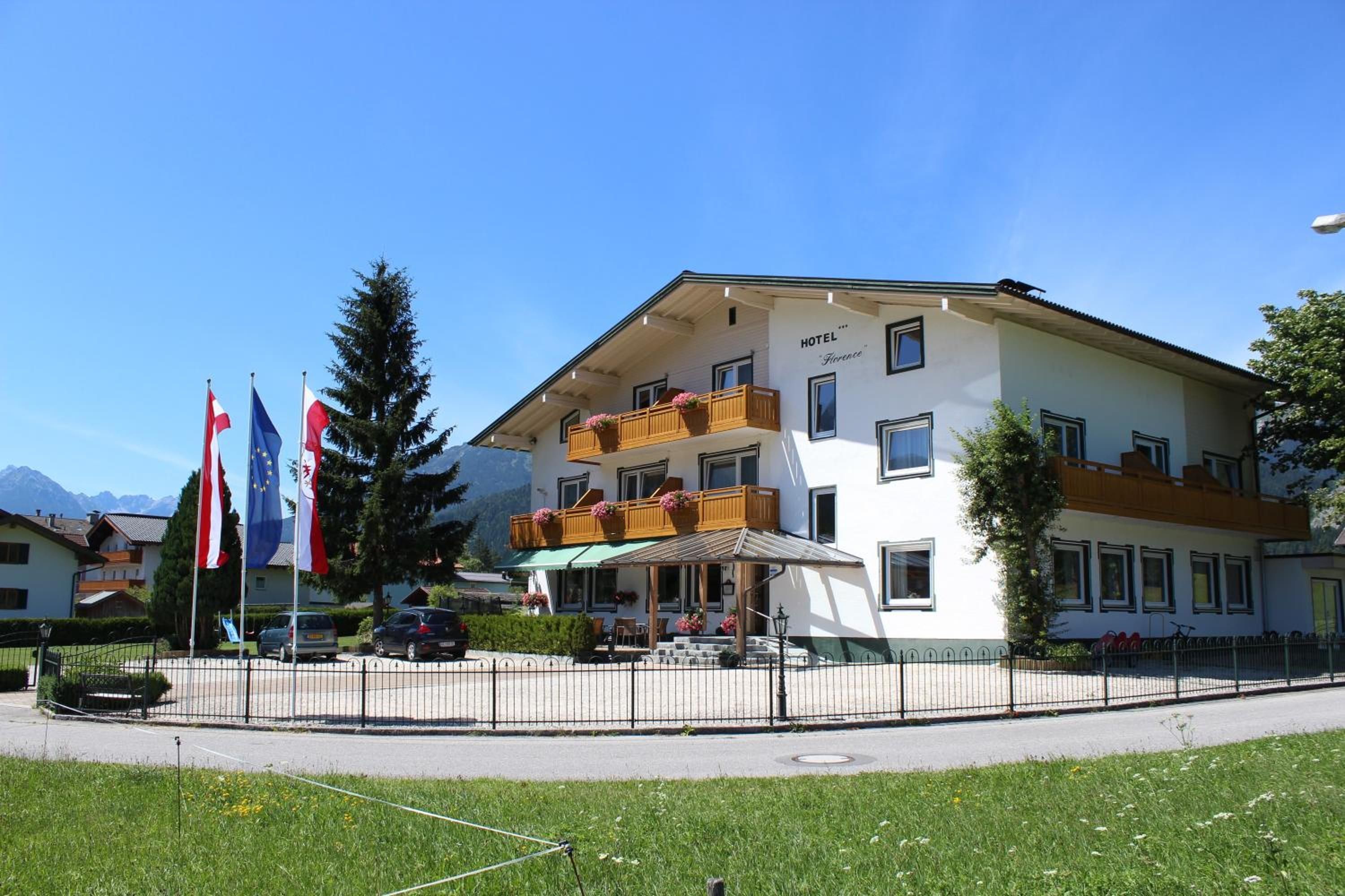 A hotel with a balcony, a sign indicating 'HOTEL Florence', and multiple flags.