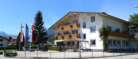 A hotel with a balcony, a sign indicating 'HOTEL Florence', and multiple flags.