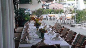 Un espace de restauration en plein air avec des tables dressées pour le repas, des chaises et une enseigne indiquant un café et un restaurant.