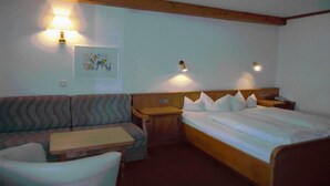 Une chambre d’hôtel comprenant un lit, un canapé, une petite table et deux lampes fixées au mur.