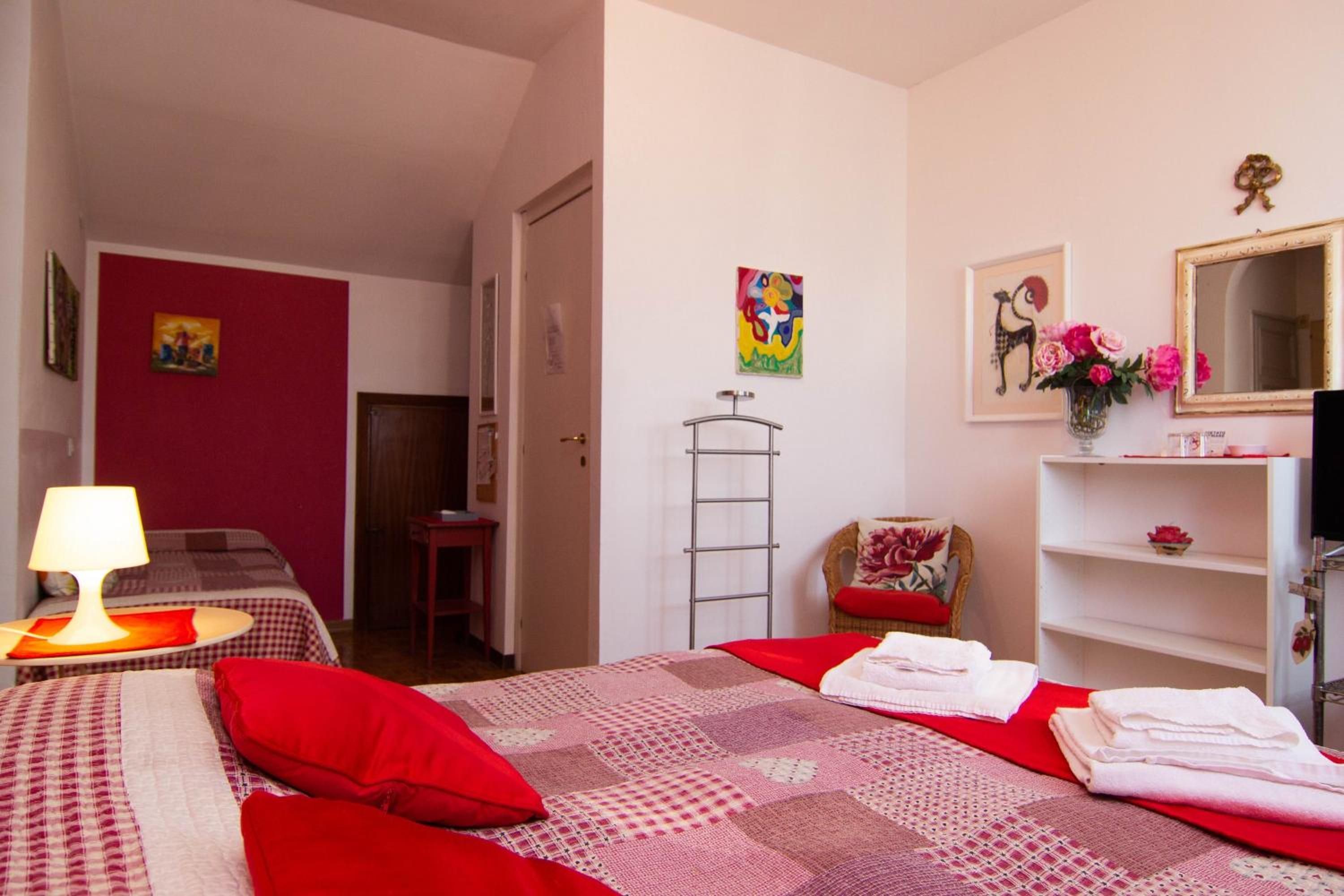 A hotel room with a bed, a desk, a chair, a mirror, and a shelf with towels.