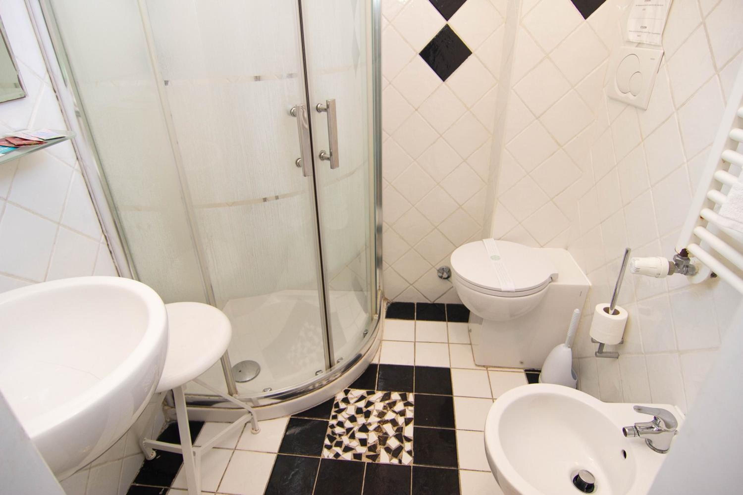 Un baño con cabina de ducha de vidrio, inodoro, bidé y lavamanos.
