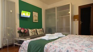 A hotel room with a bed, a television, a window, and a door.