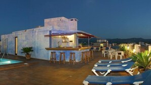 Uma área de piscina no terraço, com espreguiçadeiras e um bar.