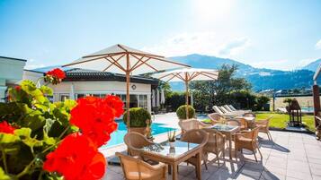 Un espace aménagé au bord de la piscine, avec des meubles d’extérieur et une vue sur les montagnes.