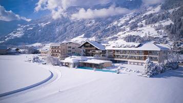 Une station de montagne enneigée, avec un grand bâtiment doté de nombreux balcons et d’une piscine.