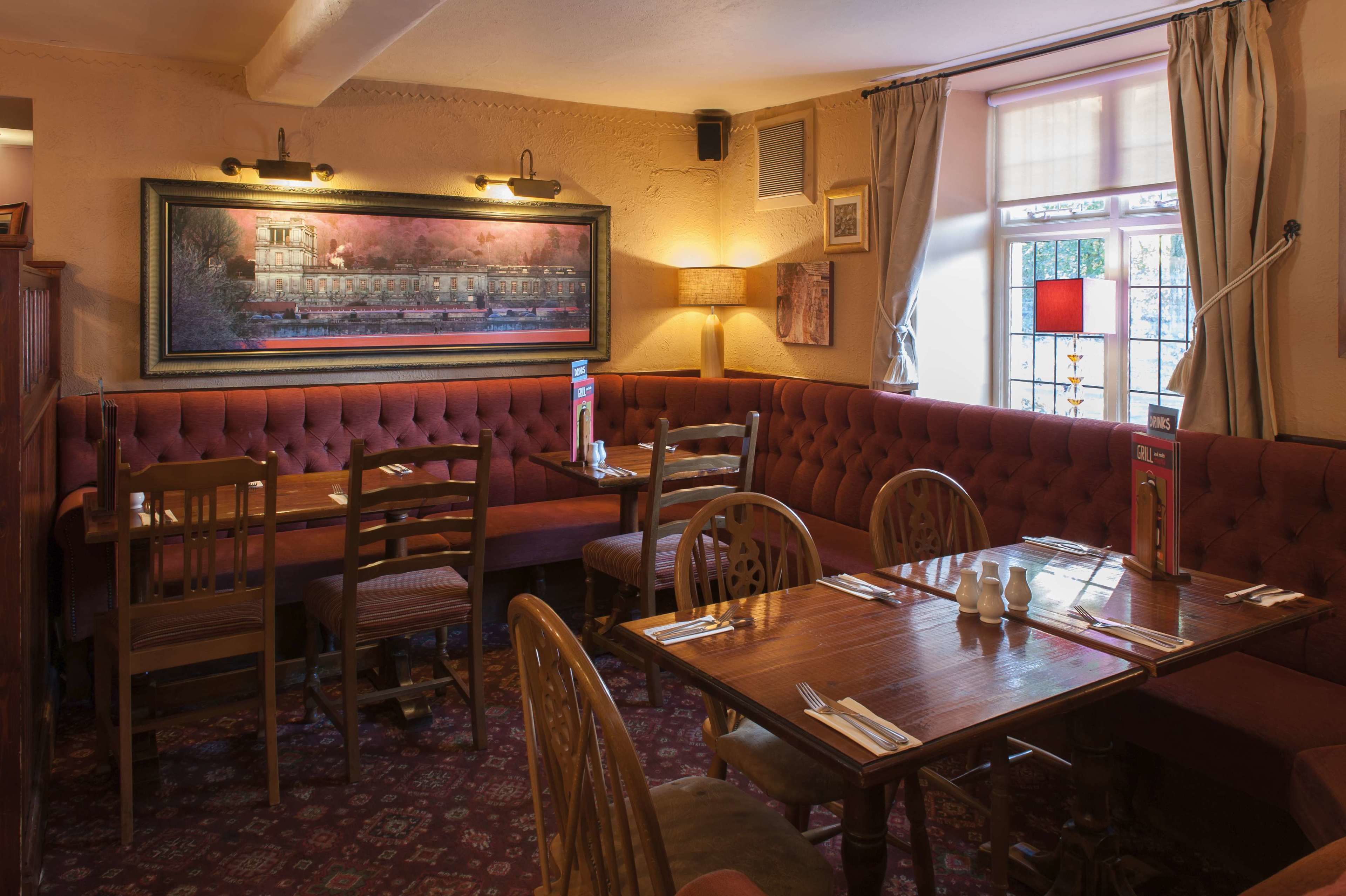 A dining area with a wooden table, cushioned bench seating, and a framed painting on the wall.