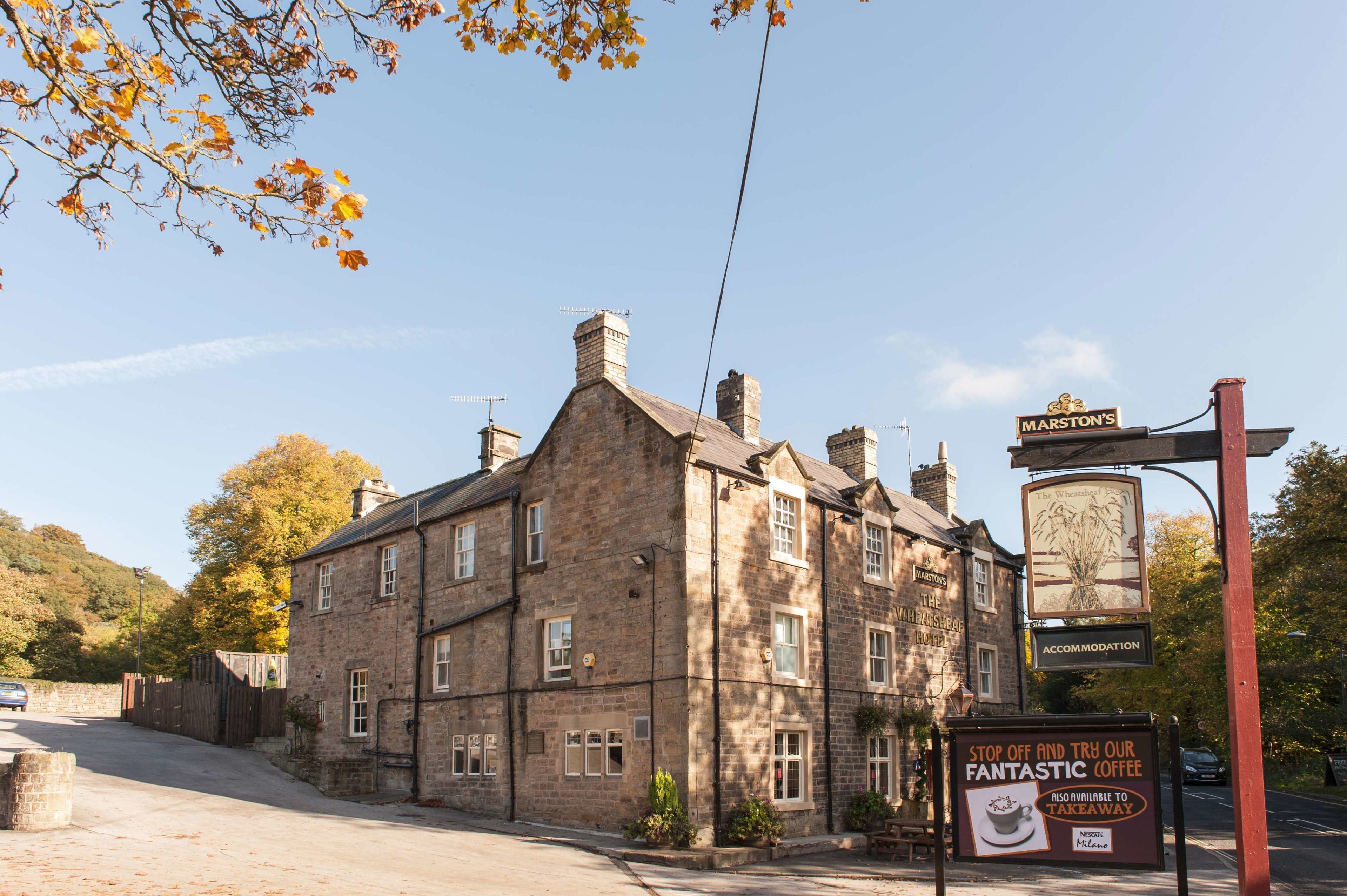 A stone building with a sign for Marston's, a pub, and an advertisement for fantastic coffee.
