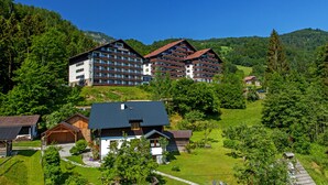 Un hotel con varias edificaciones, incluyendo una construcción grande con balcones y un edificio más pequeño con techo inclinado.