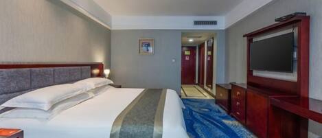 Habitación de hotel con cama, televisión, escritorio y piso alfombrado.
