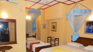 Quarto de hotel com duas camas, uma mesa de madeira e uma janela com cortina.