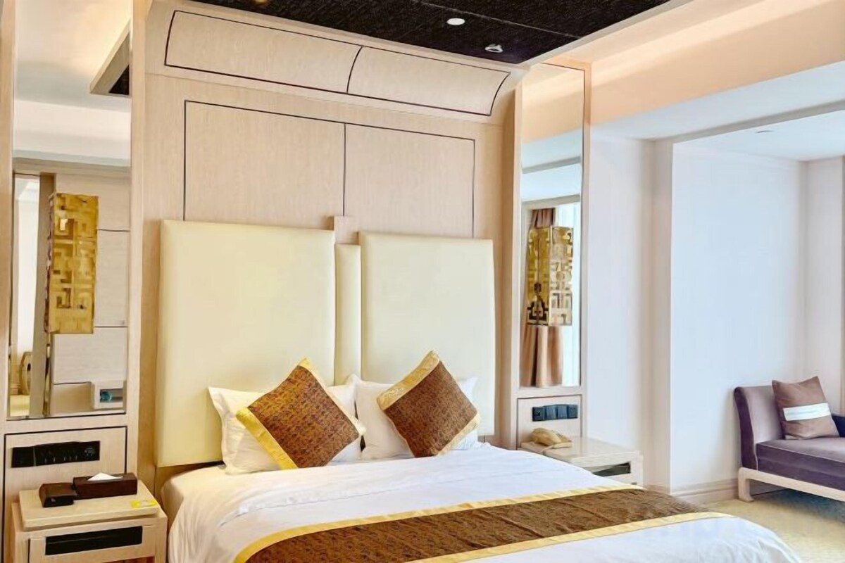 Une chambre d’hôtel moderne avec un grand lit, une table de chevet, une chaise et un grand miroir.