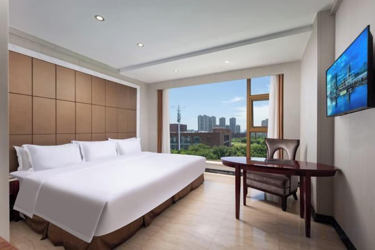 Une chambre d’hôtel avec un grand lit, une table à manger et une vue sur la ville.