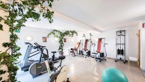 Un gimnasio con diverso equipo de ejercicio, que incluye cintas de correr, bicicletas estáticas y máquinas de pesas.