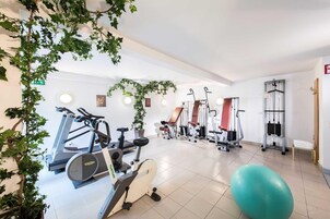 Un gimnasio con diverso equipo de ejercicio, que incluye cintas de correr, bicicletas estáticas y máquinas de pesas.