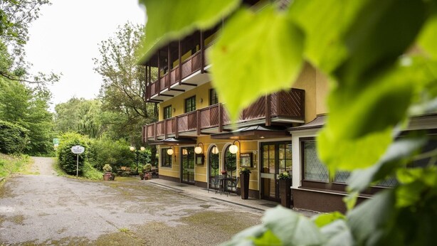 Un hotel de dos pisos con zona de estar al aire libre y una entrada visible.