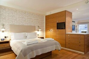 A modern hotel room with a large bed, wooden wardrobe, and a flat-screen TV mounted on the wall. - Blueprint Living - 66 Turnmill Street (London)