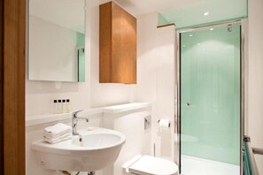 A modern bathroom with a white sink, mirror, and glass shower enclosure. - Blueprint Living - 66 Turnmill Street (London)