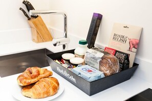 A kitchen counter with a black box containing food items, a plate with croissants, and a knife block. - Blueprint Living - 66 Turnmill Street (London)
