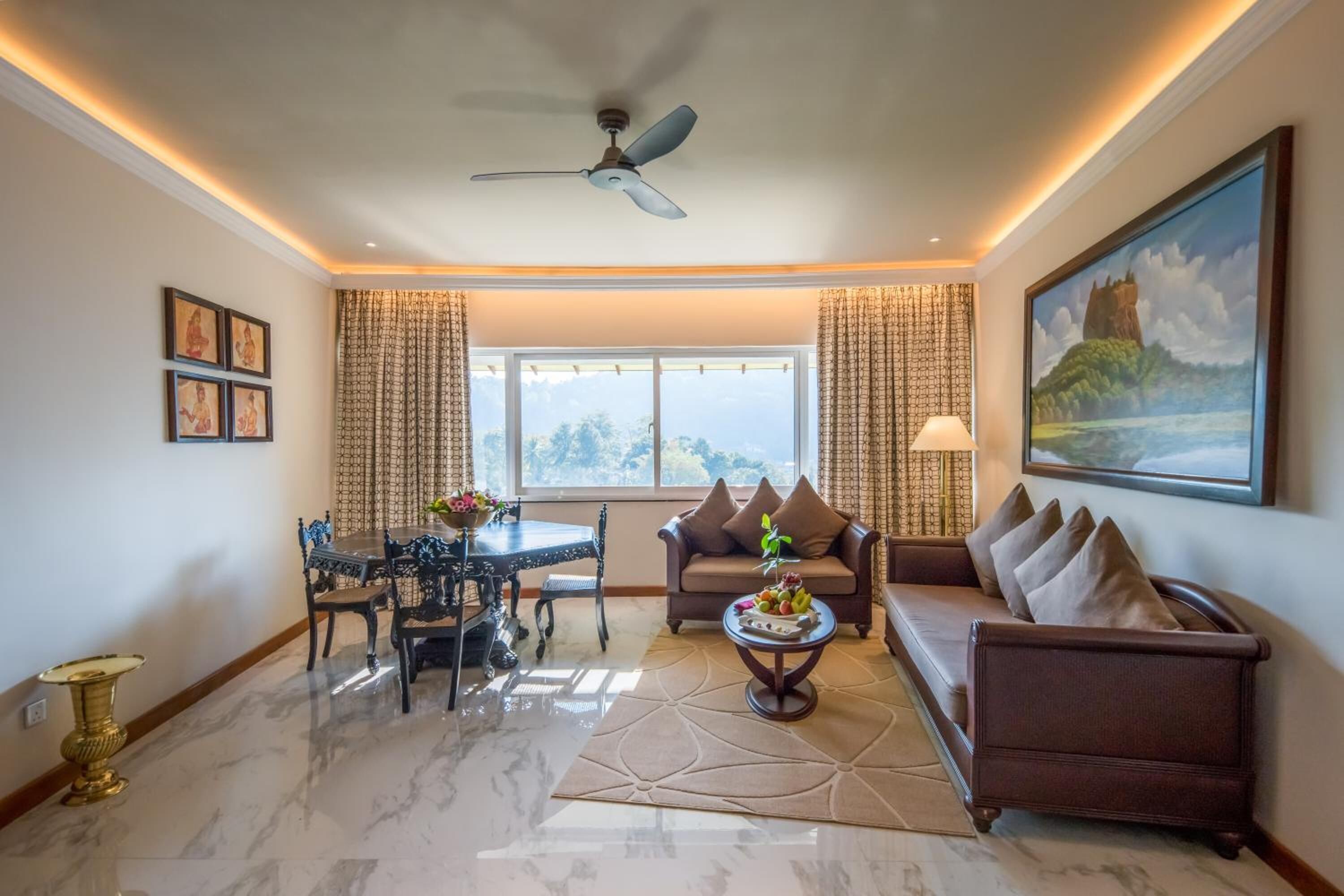 A spacious living room with a dining area, a sofa, a coffee table, and a ceiling fan.