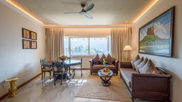 A spacious living room with a dining area, a sofa, a coffee table, and a ceiling fan.