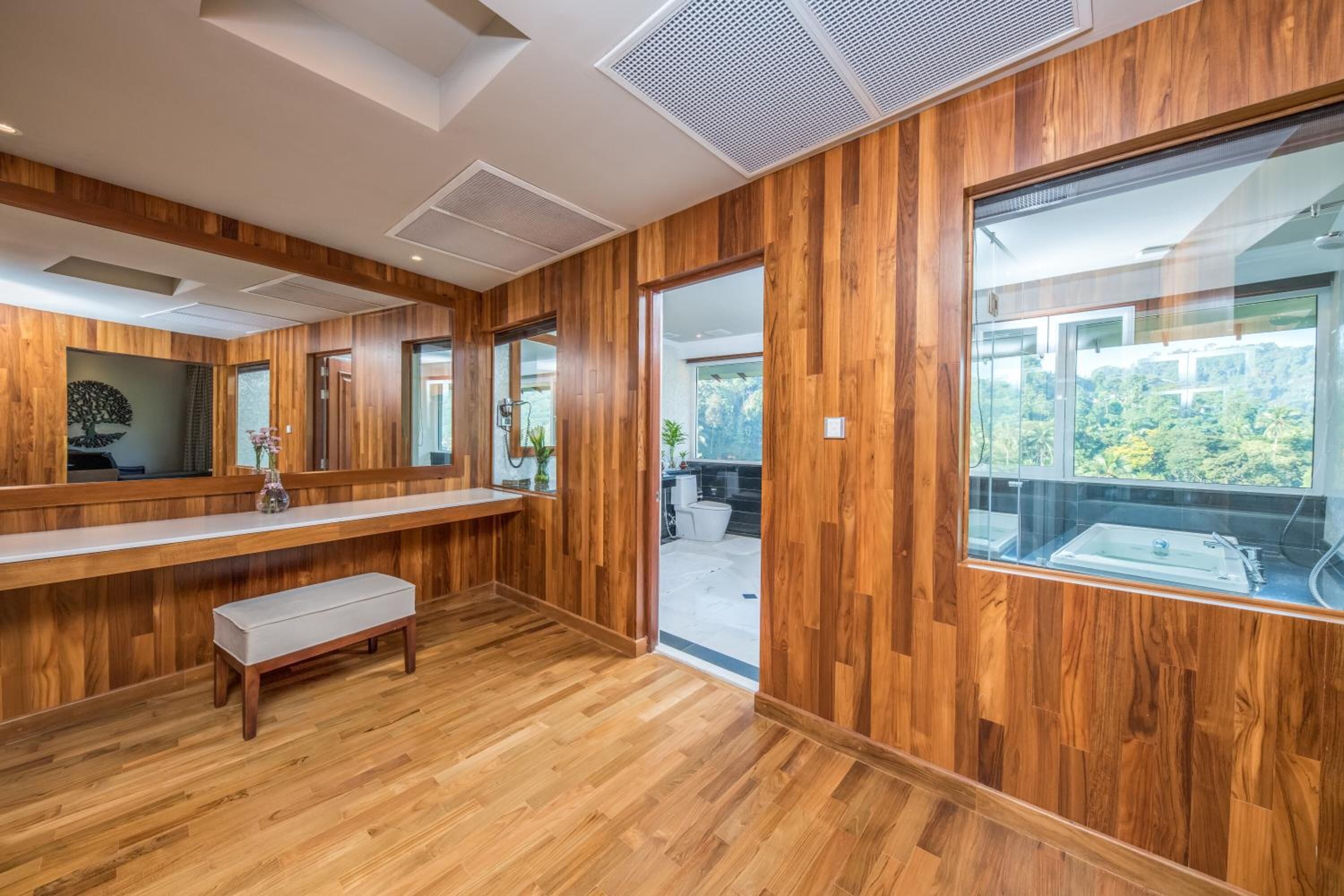 A modern bathroom with wooden paneling, a bench, a large window, and a sink.