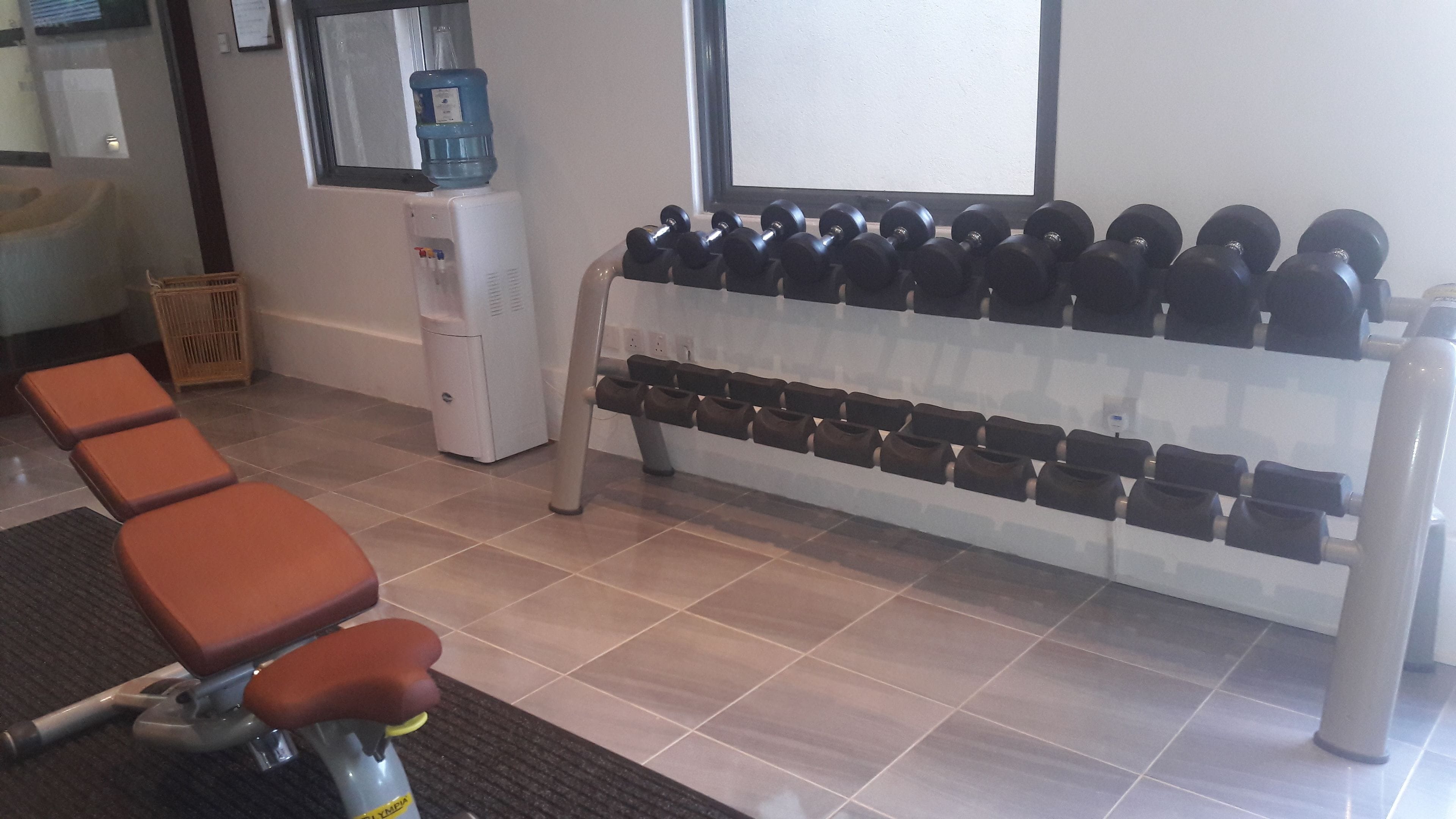 A gym with exercise equipment, a water dispenser, and seating areas.