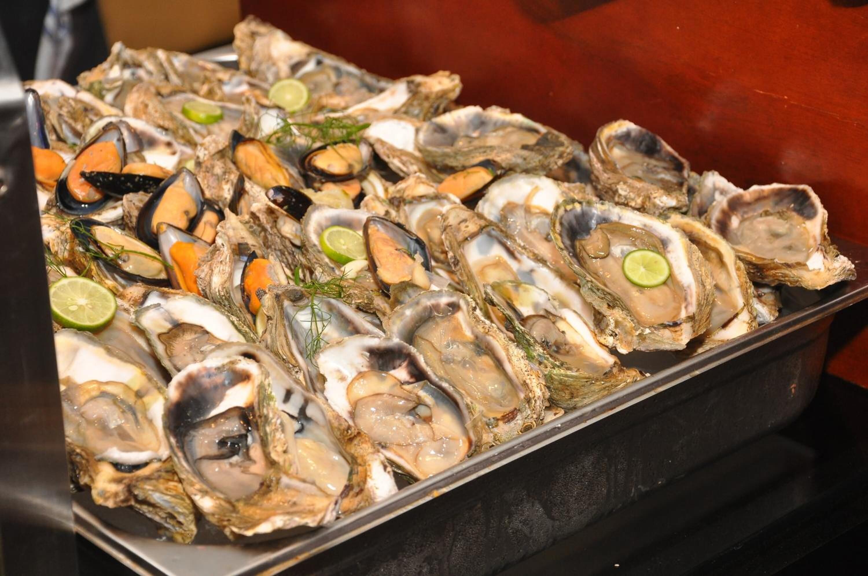 Una bandeja de ostras con cuñas de lima y hierbas.