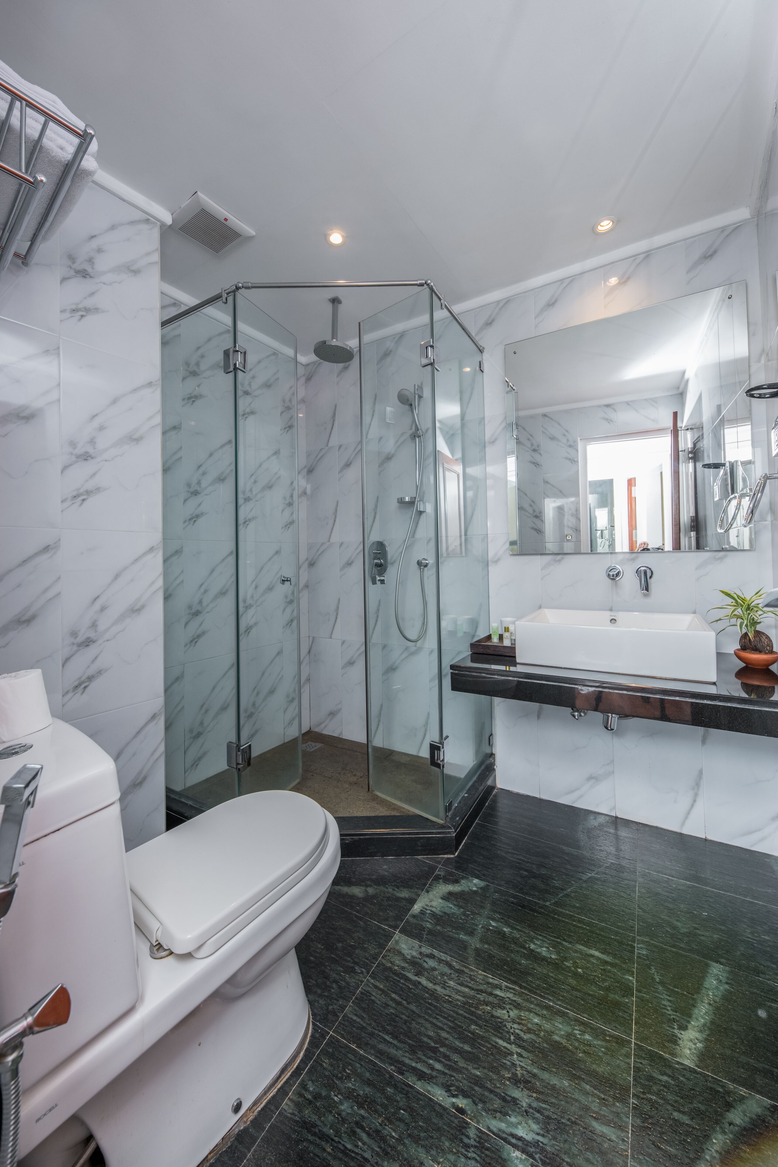A modern bathroom with a glass-enclosed shower, a white toilet, and a marble-tiled floor.