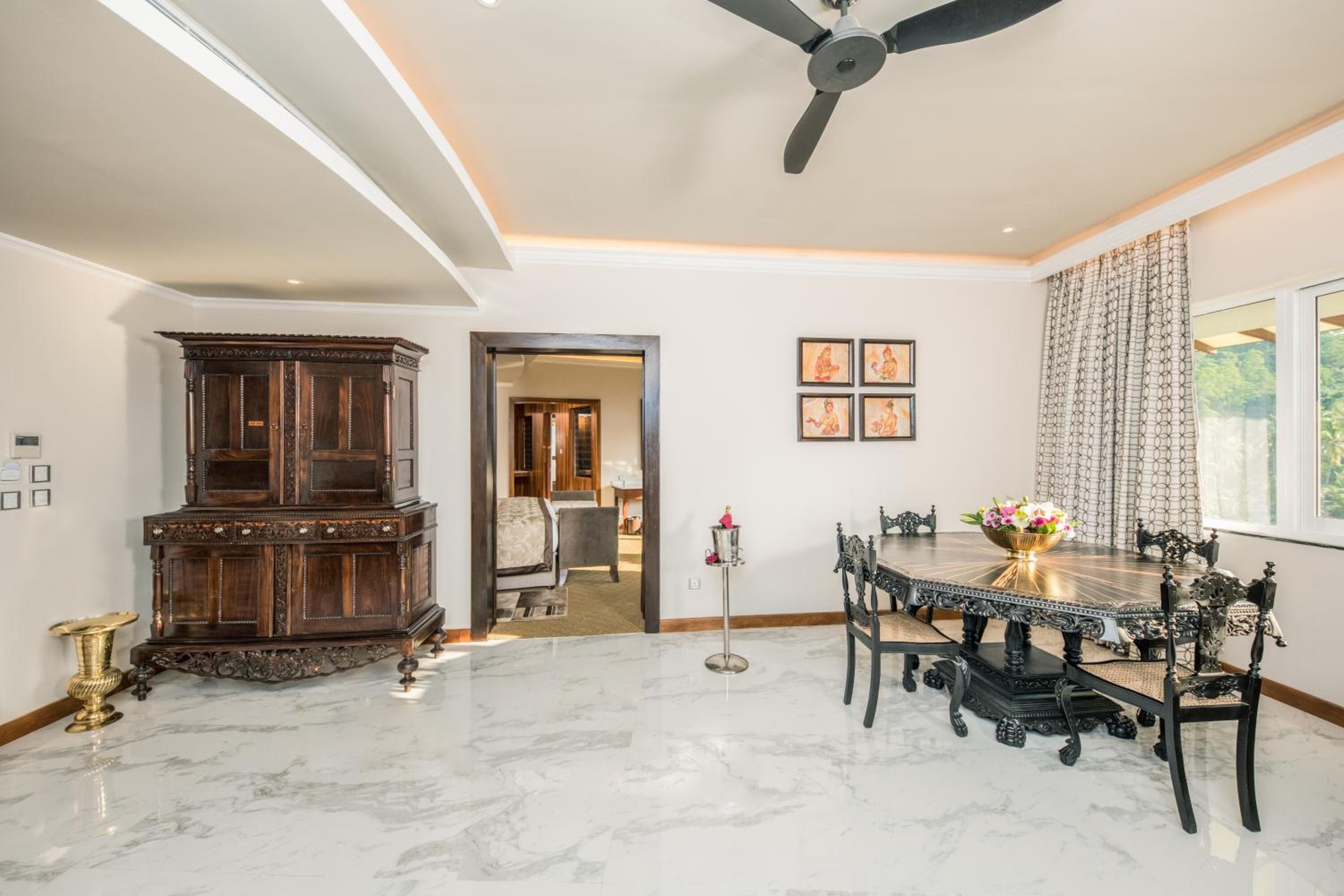 A dining area with a marble floor, a dark wooden cabinet, a ceiling fan, and a dining table with chairs.
