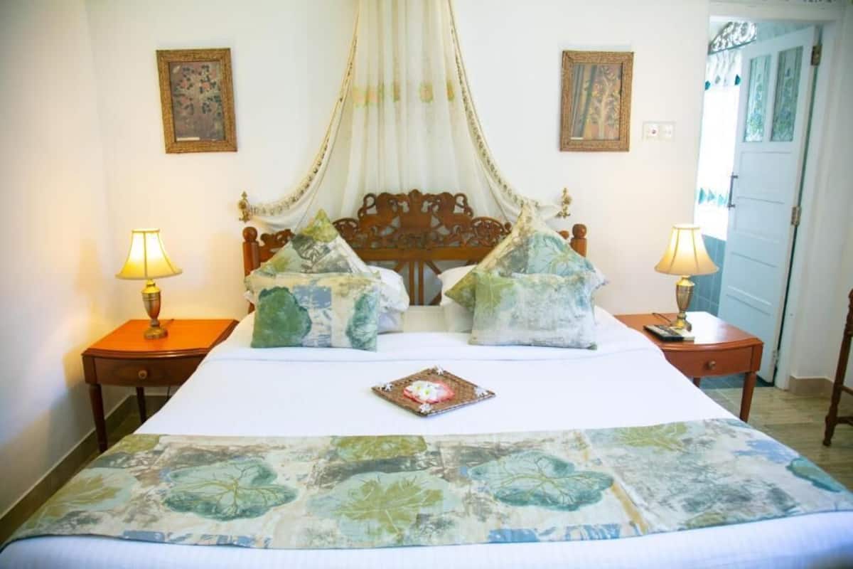 A bed with a canopy, two bedside tables with lamps, and a floral bedspread.