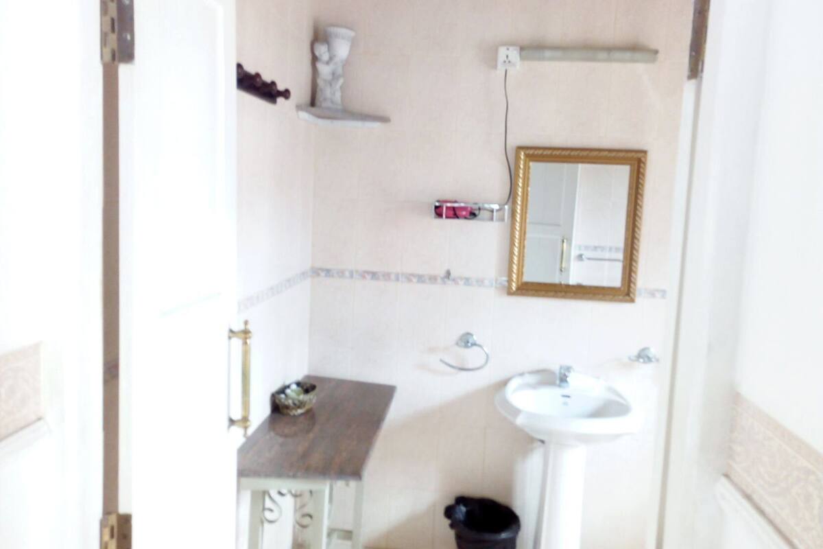 A bathroom with a sink, mirror, and a small table with a bowl.