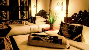 A hotel room with a large bed, two smaller beds, a nightstand with a lamp, and a potted plant. - Manor House, Kandy, LKA (Harispattuwa)