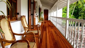 A covered porch with wooden chairs and a white railing. - Manor House, Kandy, LKA (Harispattuwa)