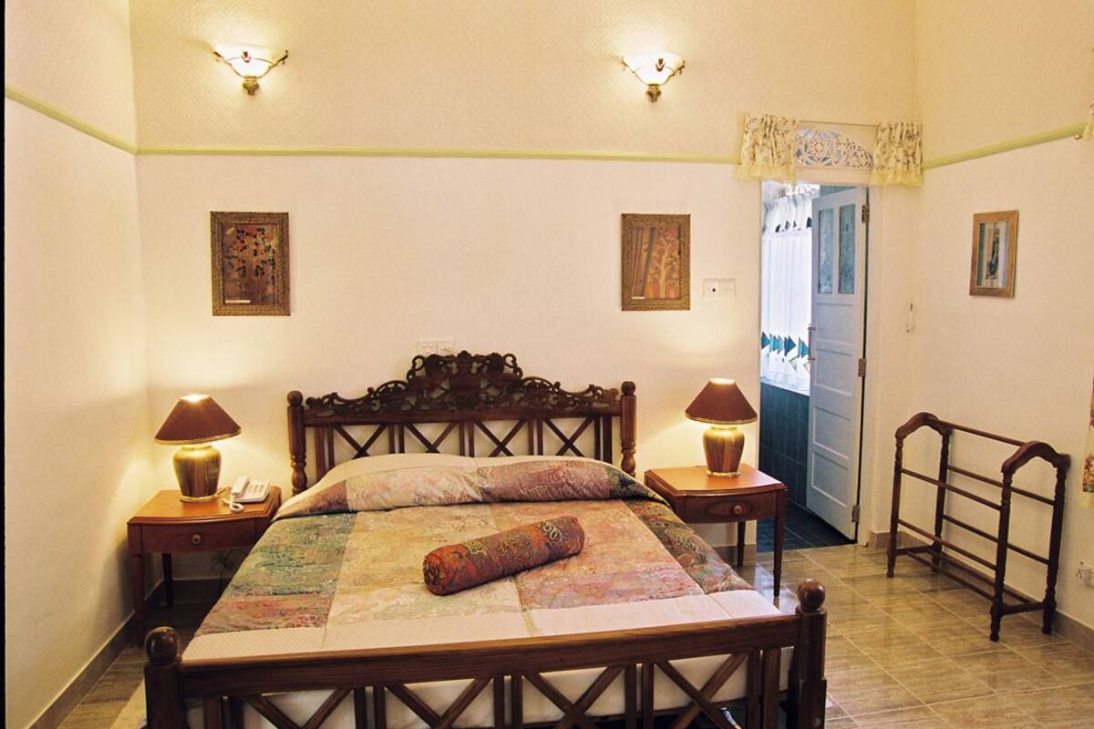 A bedroom with a wooden bed, two bedside lamps, and a door leading to another room.