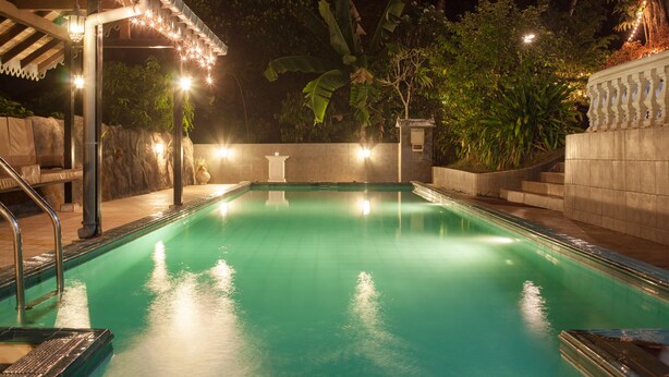 A swimming pool with a tiled deck, surrounded by plants and a stone wall. - Manor House, Kandy, LKA (Harispattuwa)