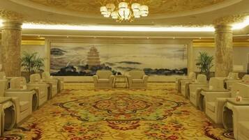 A conference room with a large carpet, chairs, a chandelier, and a mural of a pagoda.