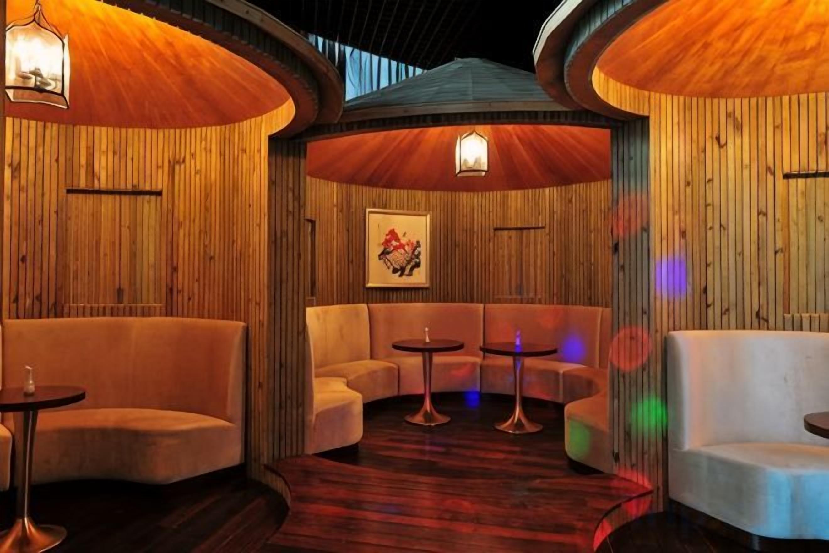 A cozy lounge area with curved seating, small tables, and ambient lighting.