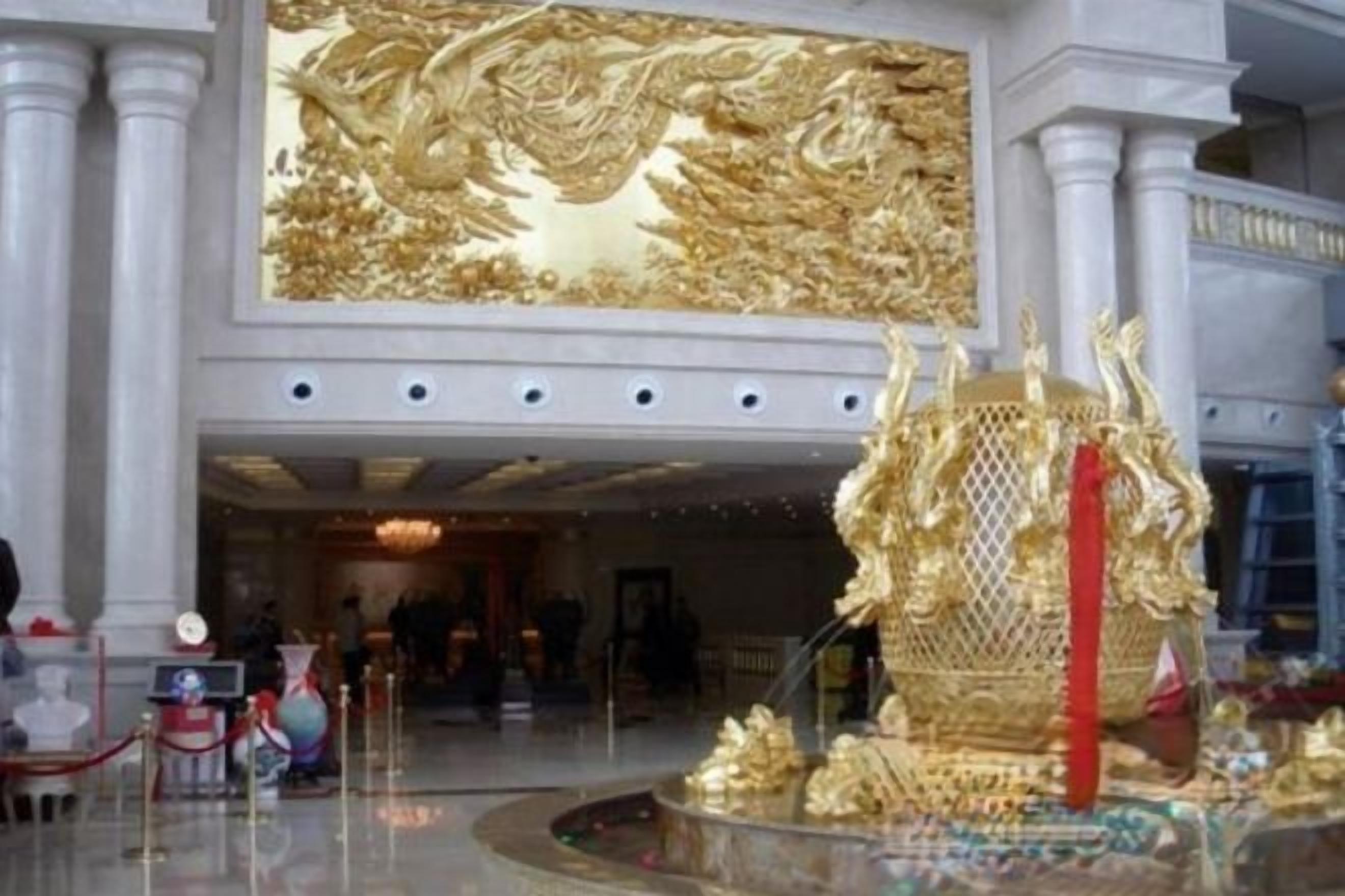 A grand lobby with a large golden mural and a decorative golden structure.