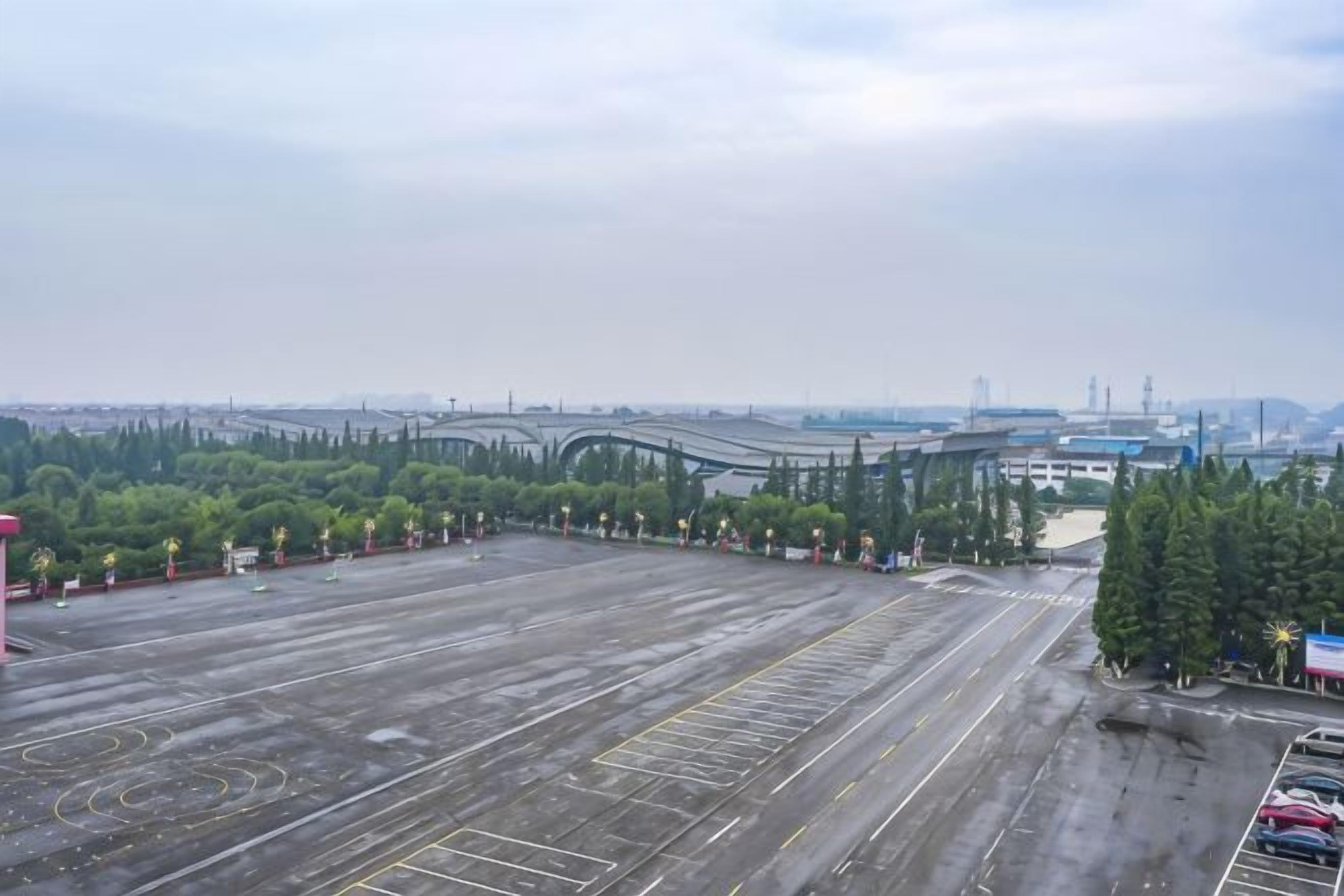 An empty parking lot with a view of a bridge and industrial buildings in the distance.