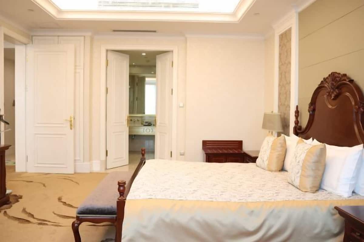 A bedroom with a large bed, a wooden bench, a nightstand, and a mirror.
