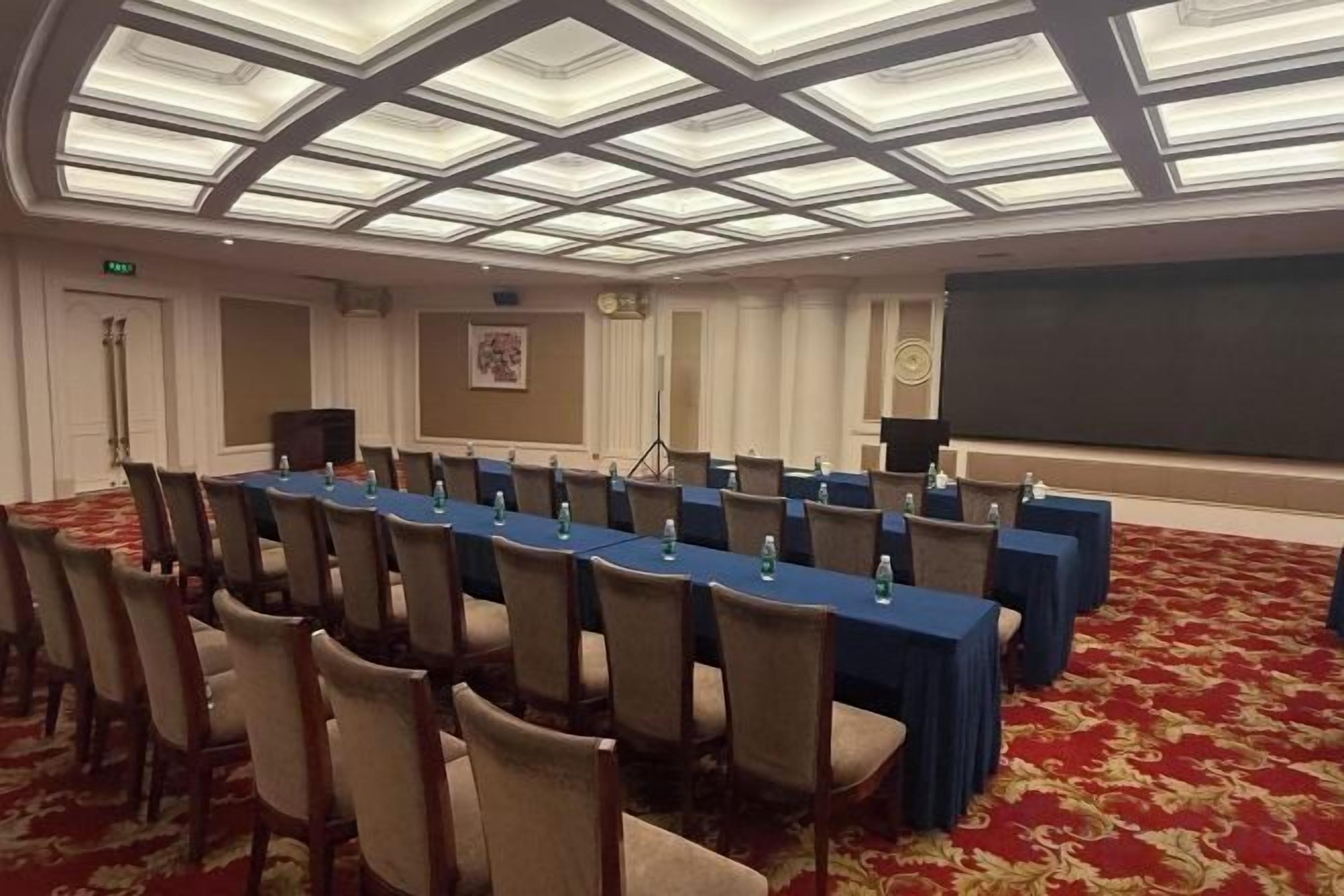 A conference room with a long table, chairs, a projector, and a screen.