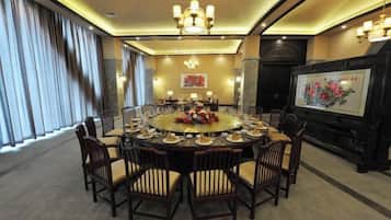 Un salón de conferencias con una mesa redonda, sillas y una lámpara de araña.