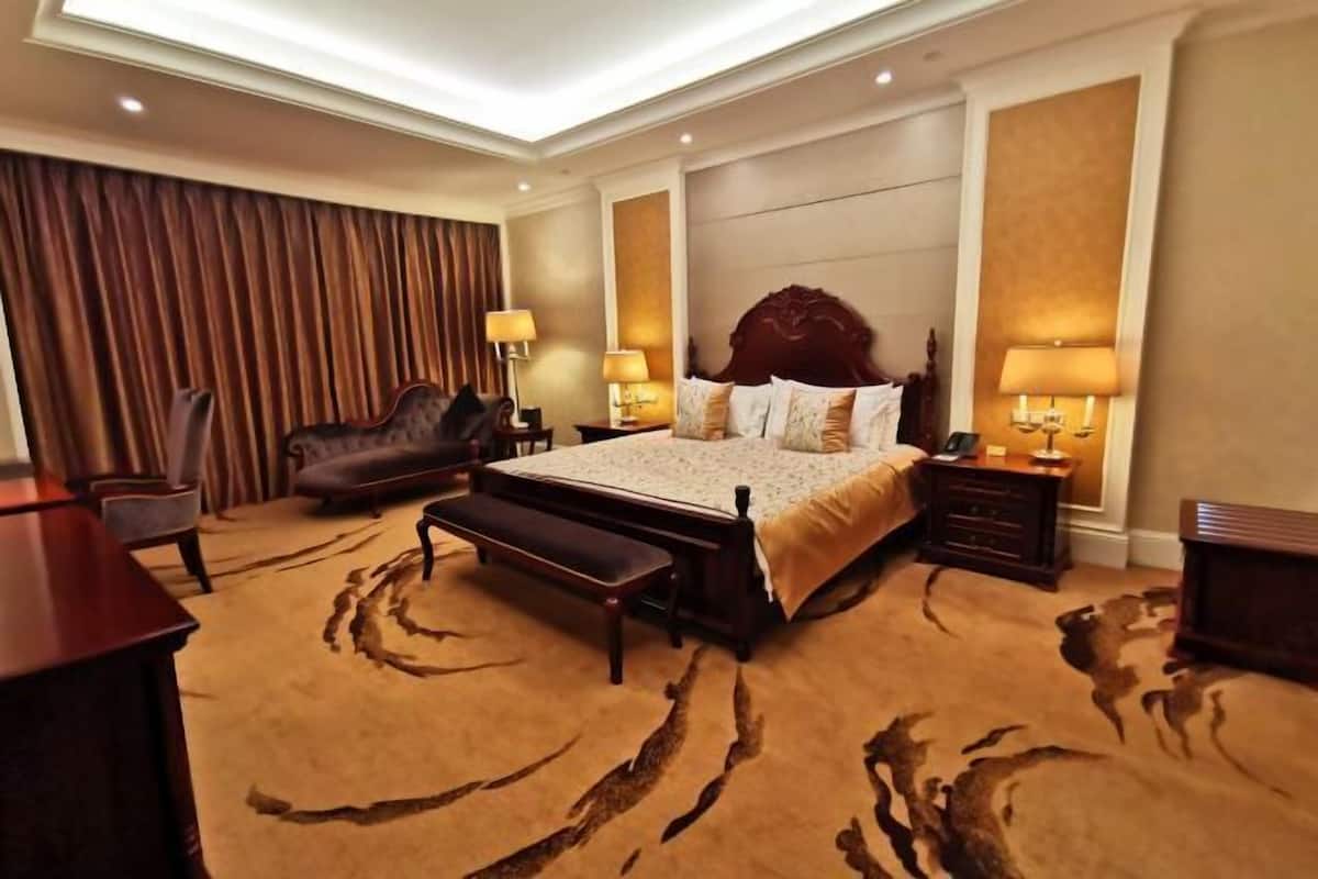 A hotel room with a large bed, a bench, a desk, and a chair.