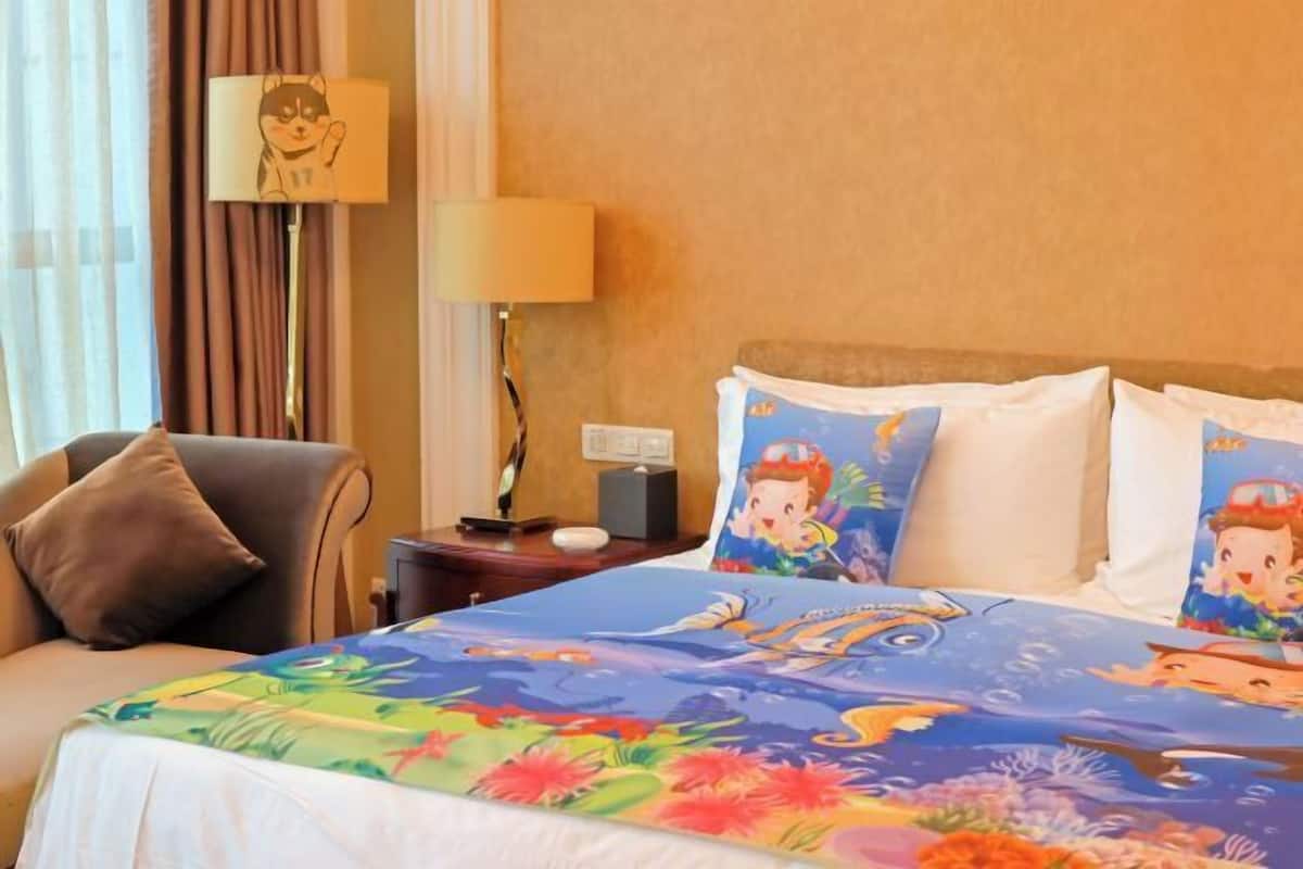 A hotel room with a bed, a chair, a nightstand, a lamp, and a wall with a picture.