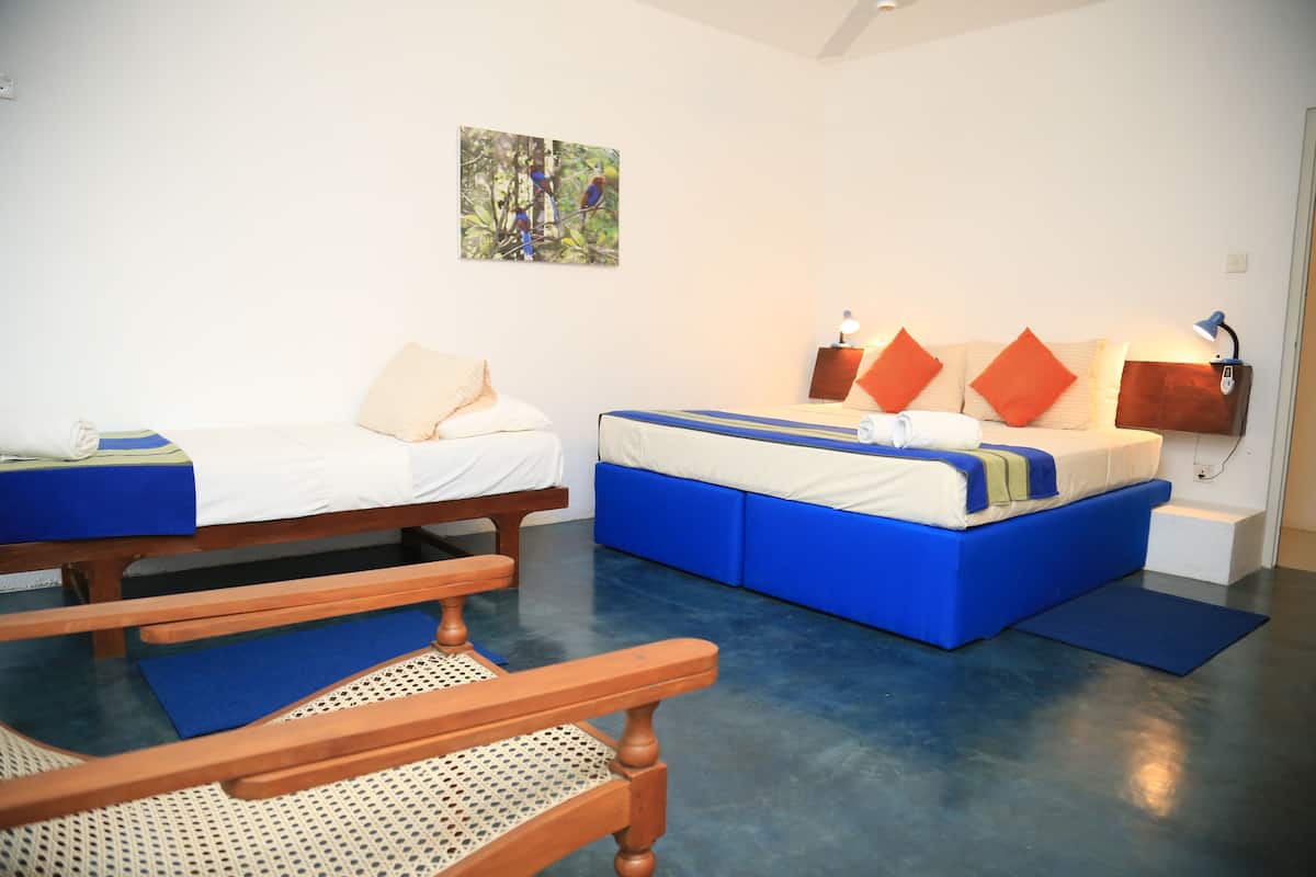 A bedroom with two beds, a wooden bench, and a blue mat.